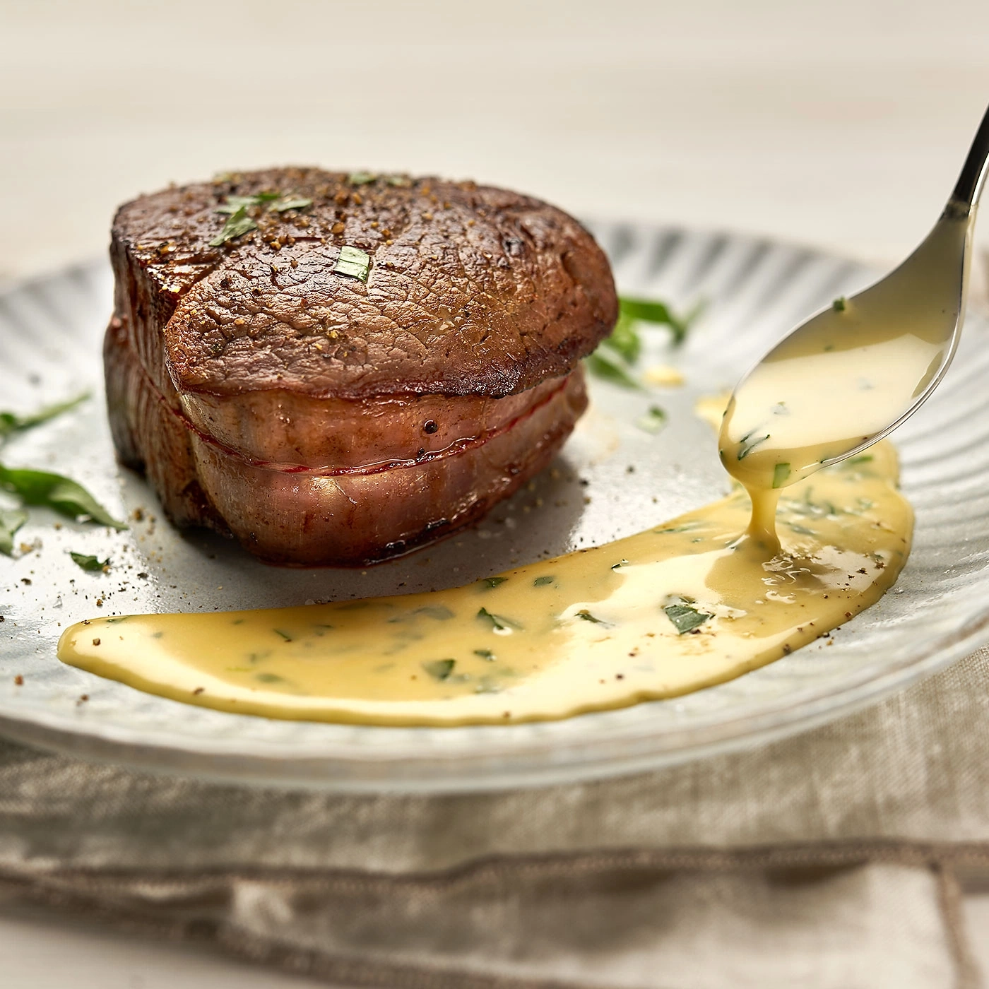 Steak grillé avec sauce sur une assiette, garni d'herbes aromatiques.