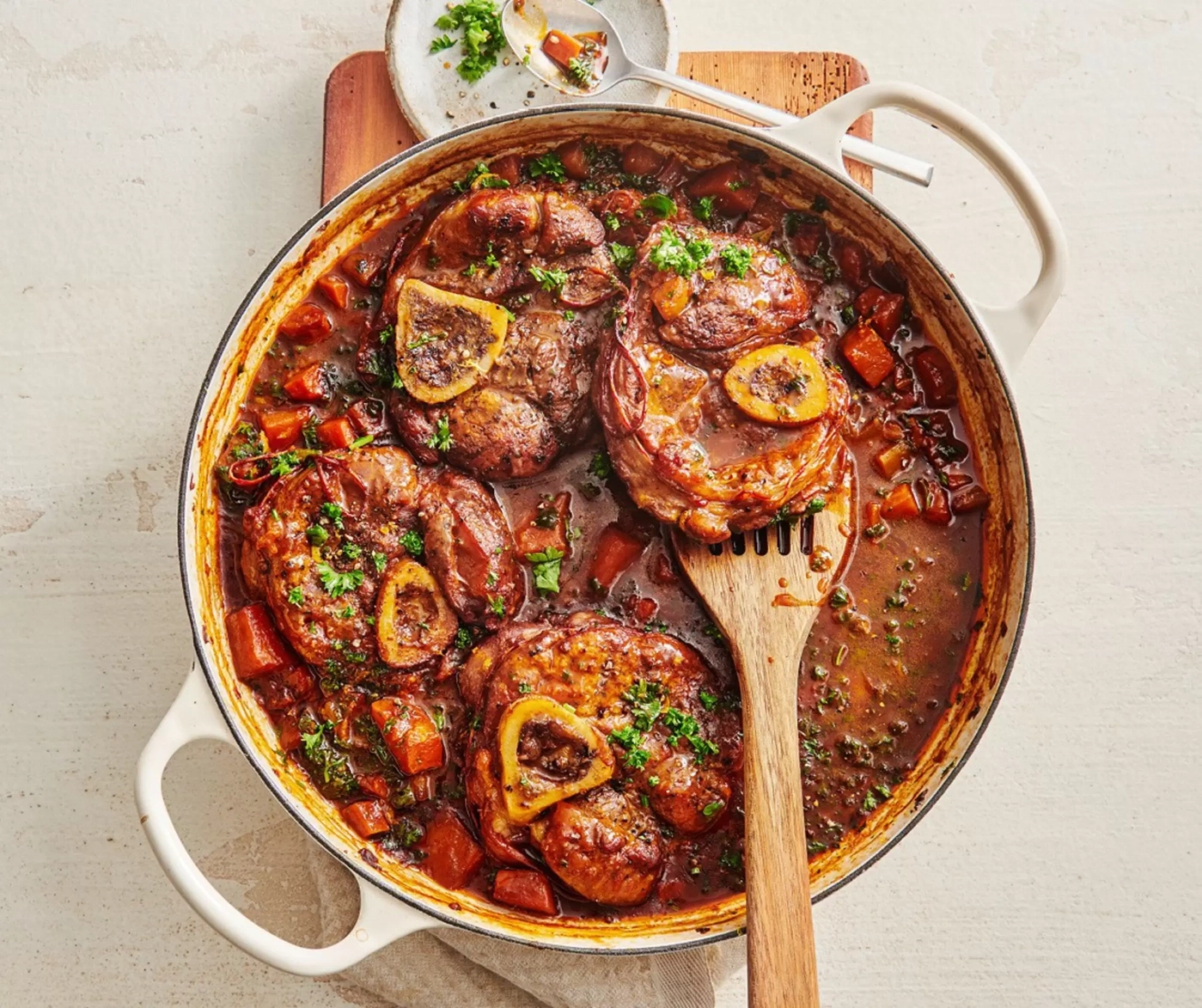 Un plat mijoté d'Osso Buco avec des légumes racines dans une cocotte.