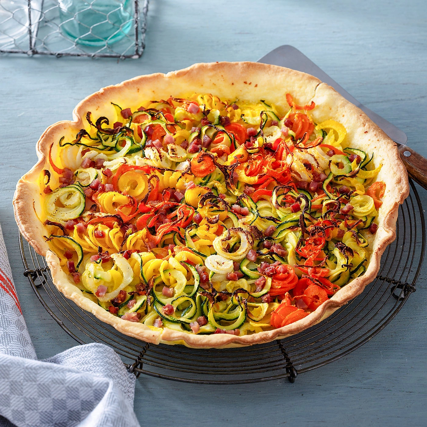 Gemüse-Quiche mit Zucchini, Tomaten und Speck auf einem Rost