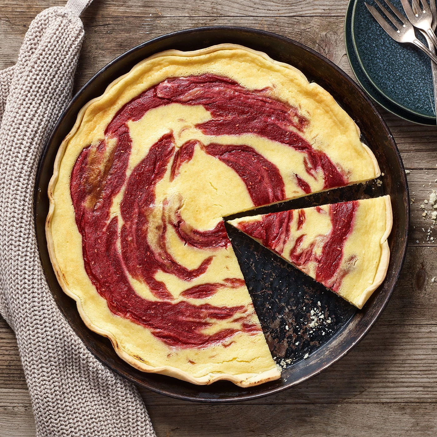 Kuchen mit roter Marmorierung, auf einem Holztisch, mit Teller und Gabeln.