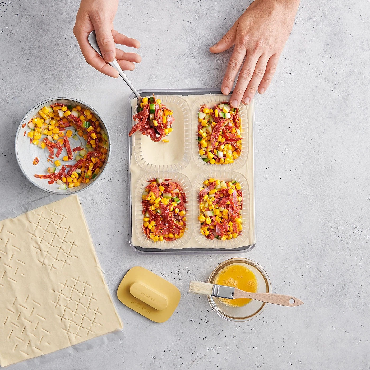 Mains remplissant des pâtisseries avec du maïs, de la saucisse et des légumes. Préparation de nourriture.
