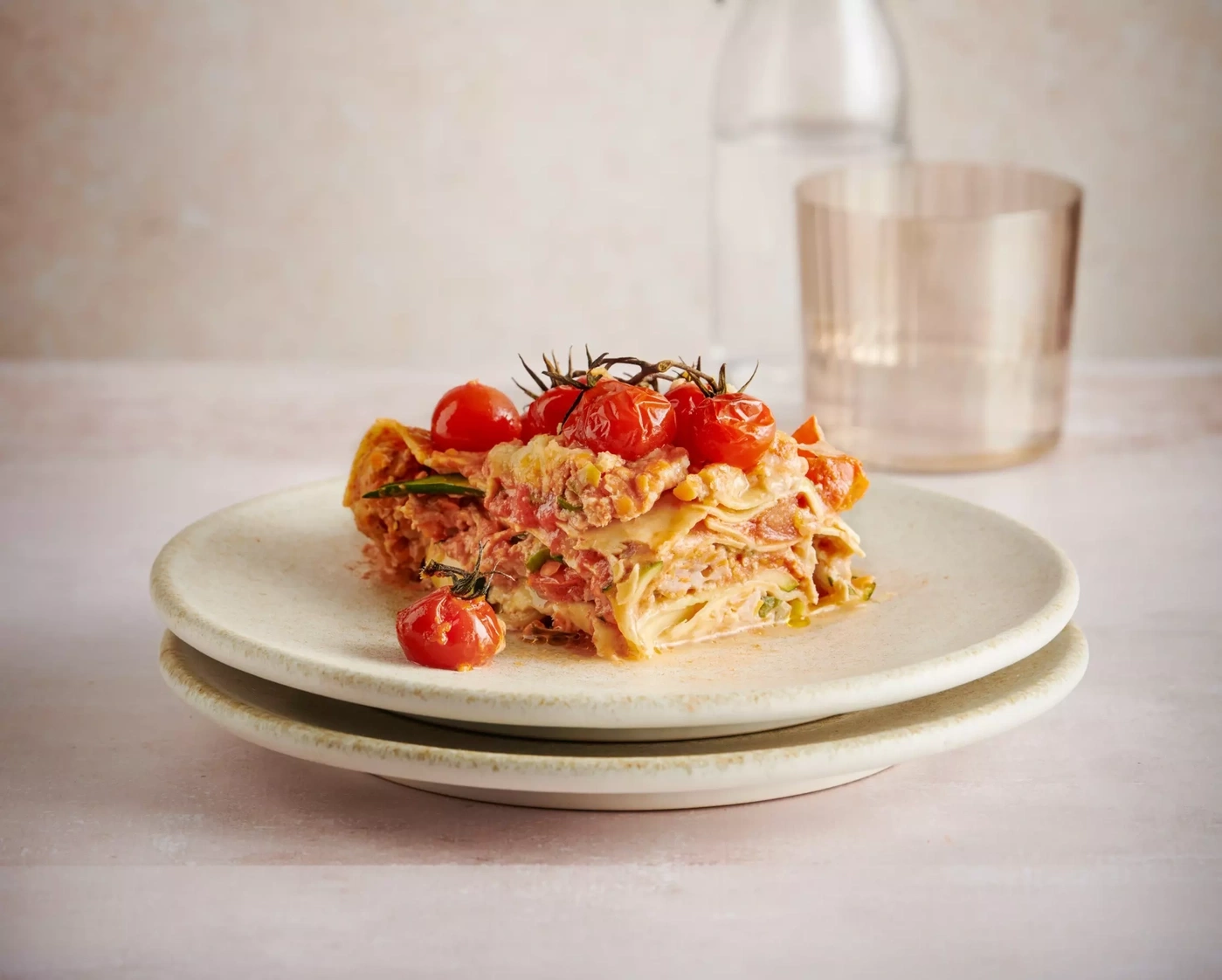 Une part de lasagne avec des tomates cerises sur une assiette