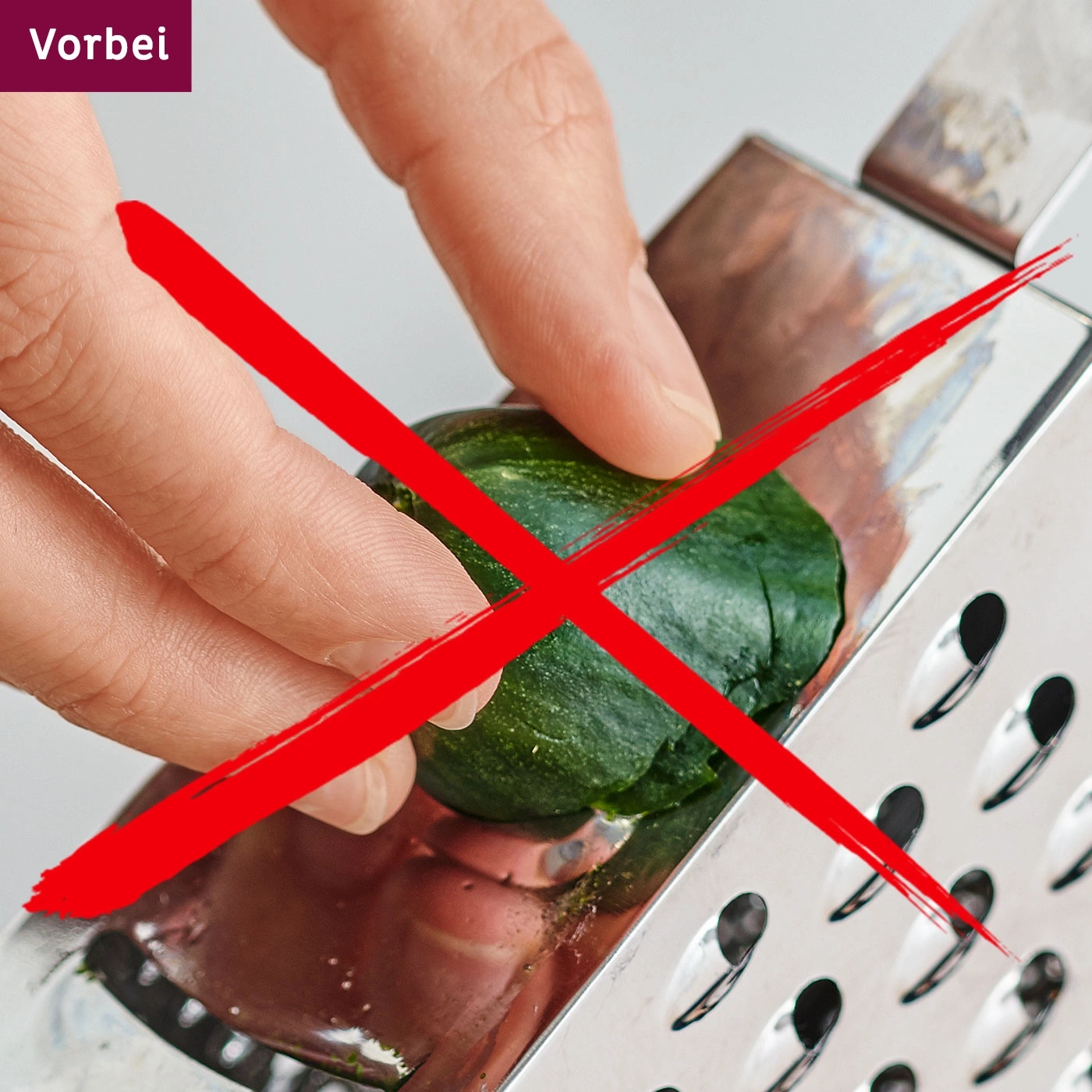Rotes X auf einem Bild von einer Hand, die eine Zucchini reibt, Vorbei.