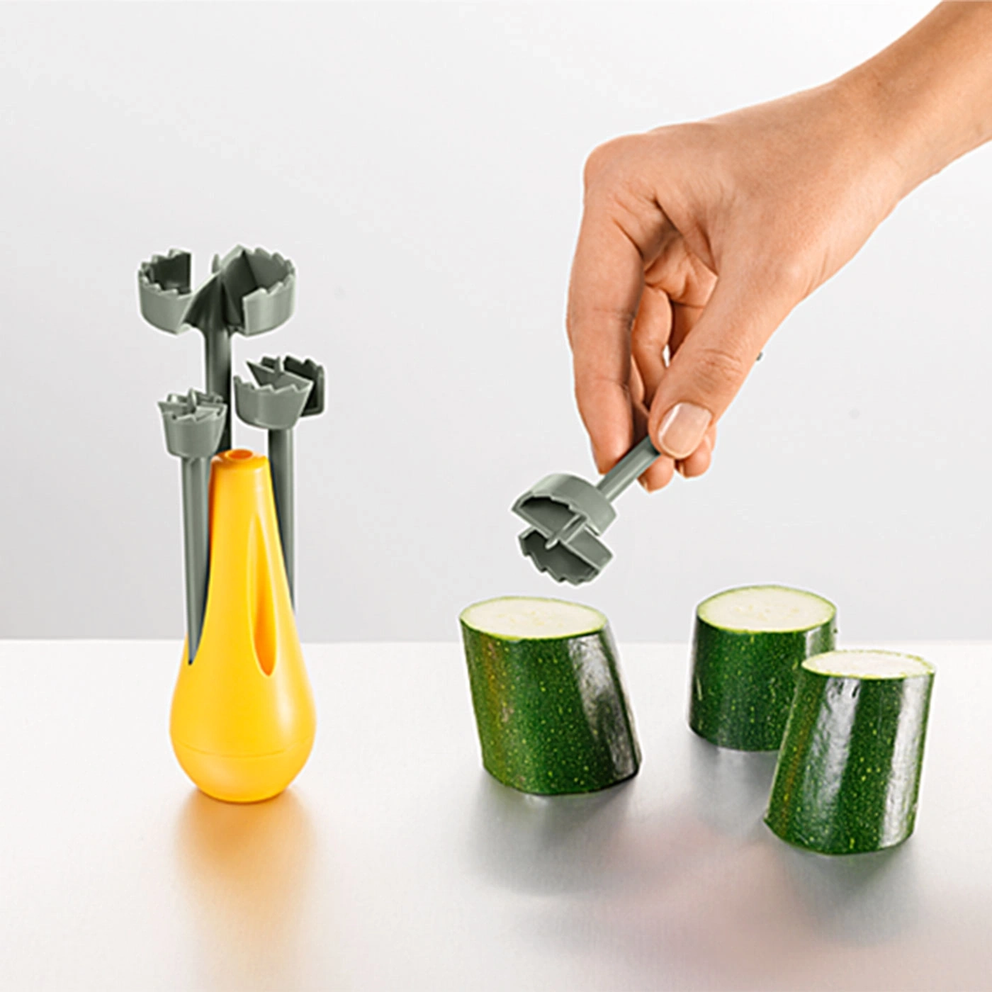 Gemüse-Schneider mit Zucchini. Hand hält Werkzeug. Gelber Halter.