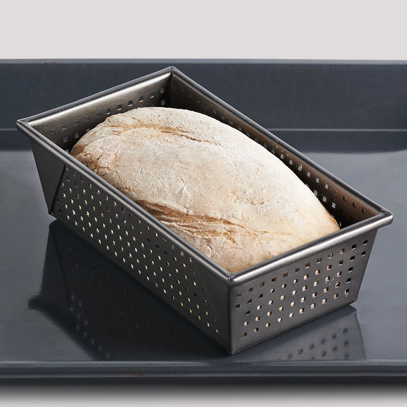 Miche de pain dans un moule à pâtisserie perforé sur un plateau. Gros plan.