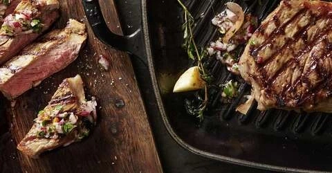 Gebratenes Steak mit Kräutern und Gemüse auf Holzbrett und Grillpfanne