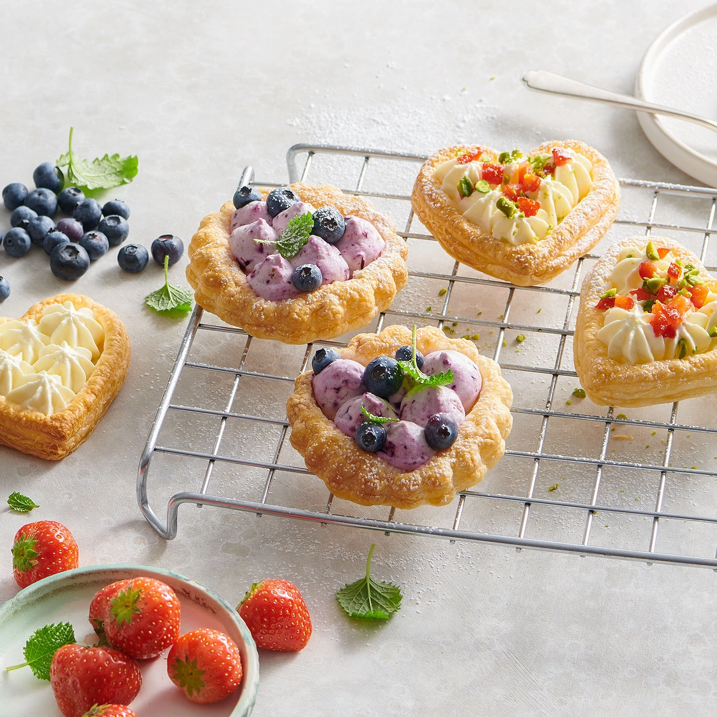 Gebäck mit Blaubeeren und Sahne, Erdbeeren, Minze, auf einem Rost