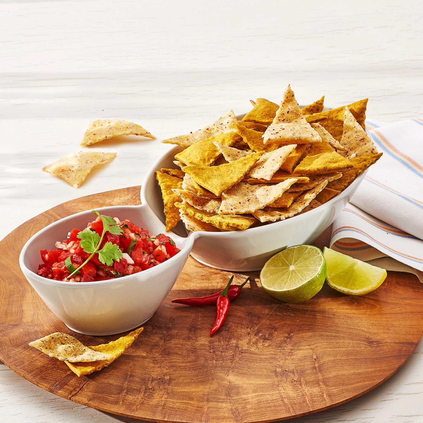 Tortilla-Chips mit Salsa, Limette und Chili auf Holzbrett
