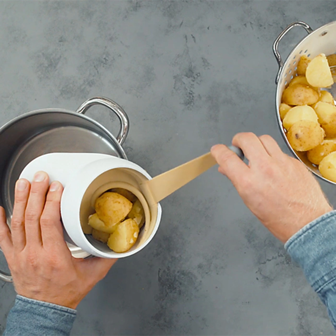 Une personne verse des pommes de terre dans un récipient blanc au-dessus d'une casserole.