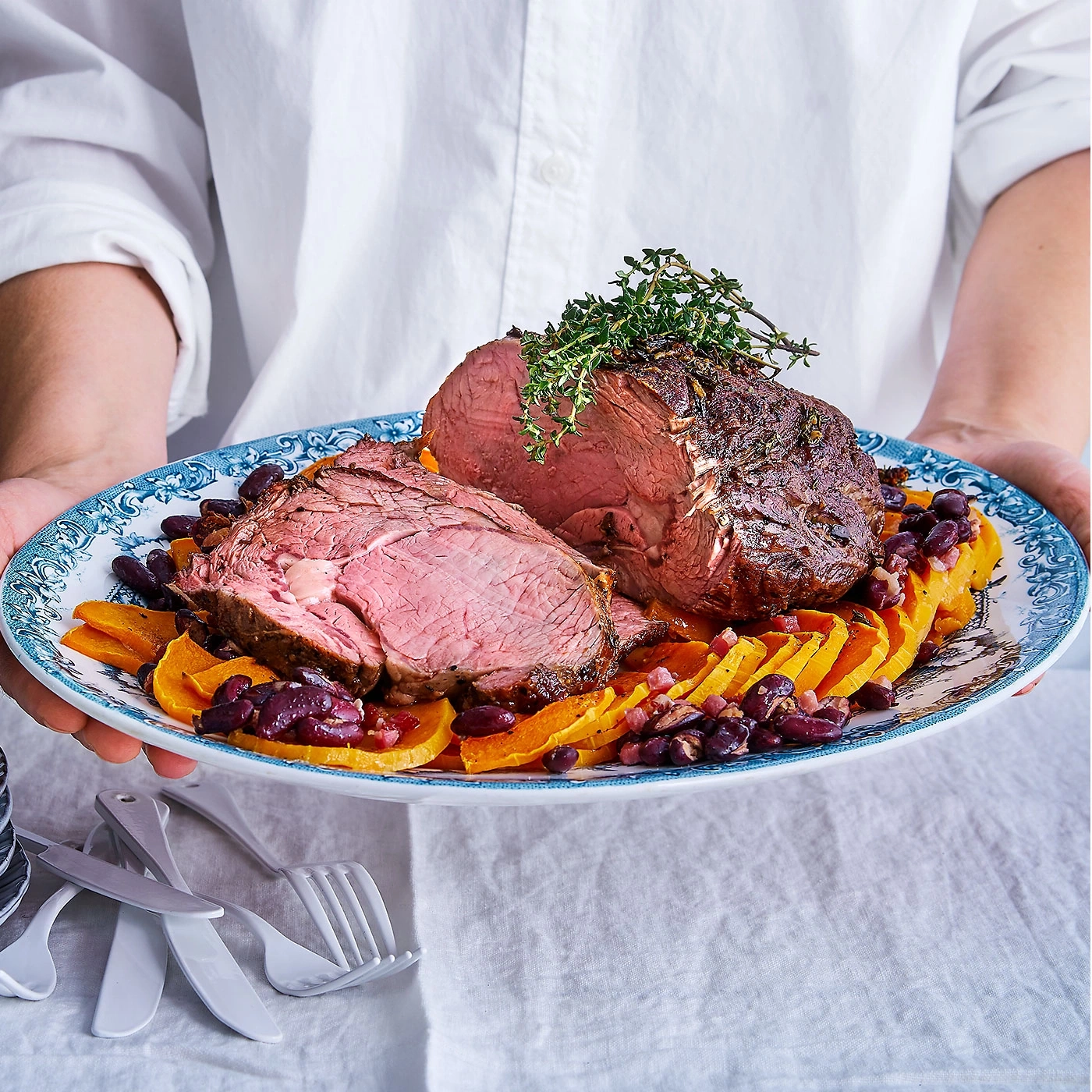 Viande rôtie sur une assiette avec légumes et haricots, servie.