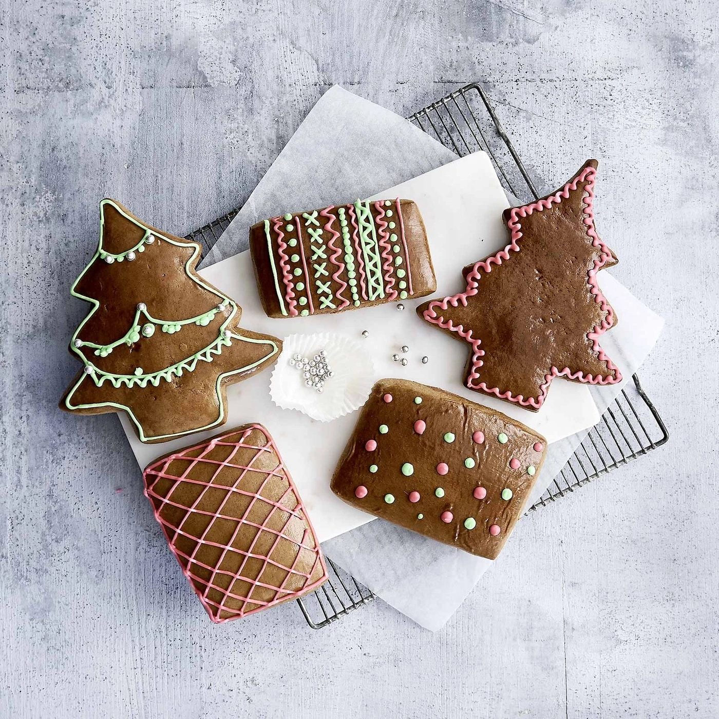 Lebkuchen in verschiedenen Formen und Dekorationen auf Backpapier und Gitter