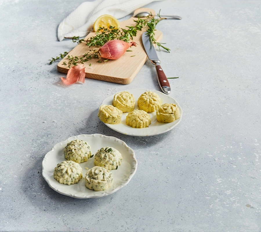 Teller mit Butter, Kräutern und Zwiebeln auf einem Tisch