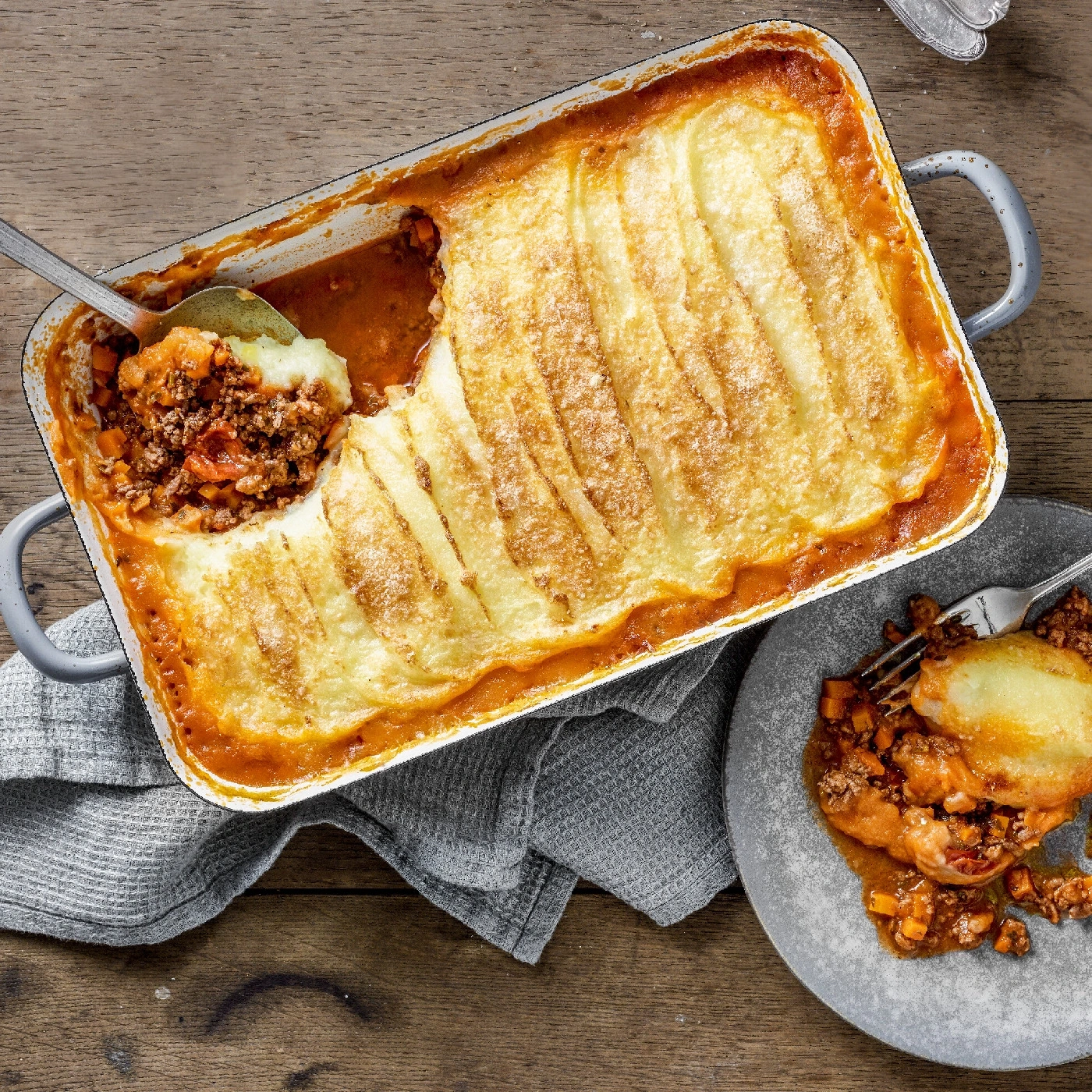 Shepherd's Pie in einer Auflaufform, serviert auf einem Teller, Holzuntergrund, lecker.