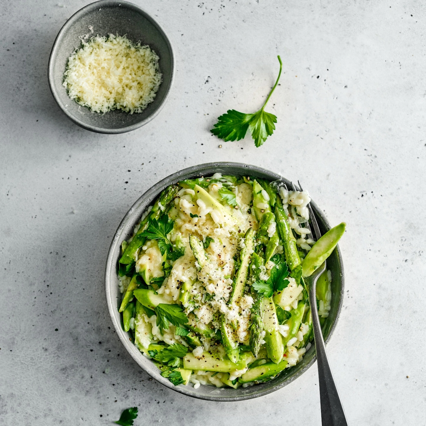 Risotto aux asperges, persil et fromage dans un bol avec une fourchette.
