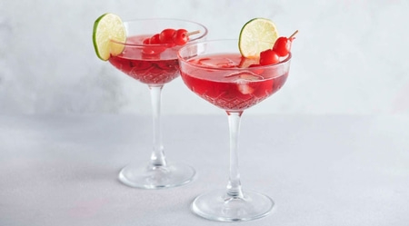 Deux cocktails avec des limes et des cerises sur fond blanc