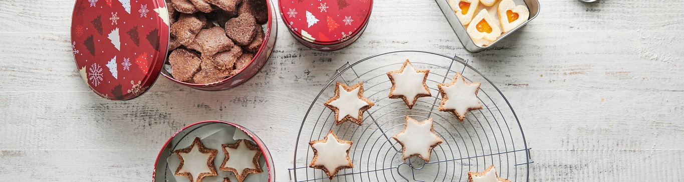 Biscuits de Noël sur une grille et dans des boîtes sur une table en bois blanc