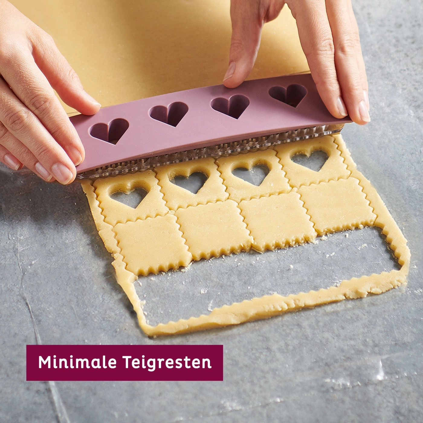 Mains coupant la pâte avec un emporte-pièce en forme de cœur, restes de pâte minimes