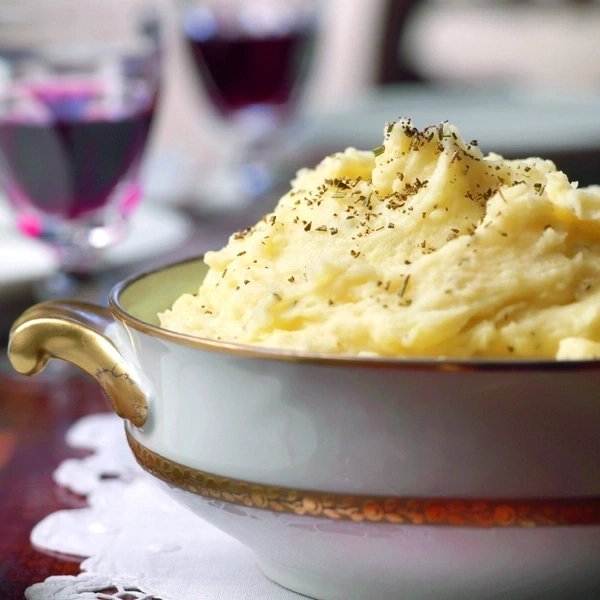Nahaufnahme von Kartoffelpüree in einer Schüssel mit Wein im Hintergrund.