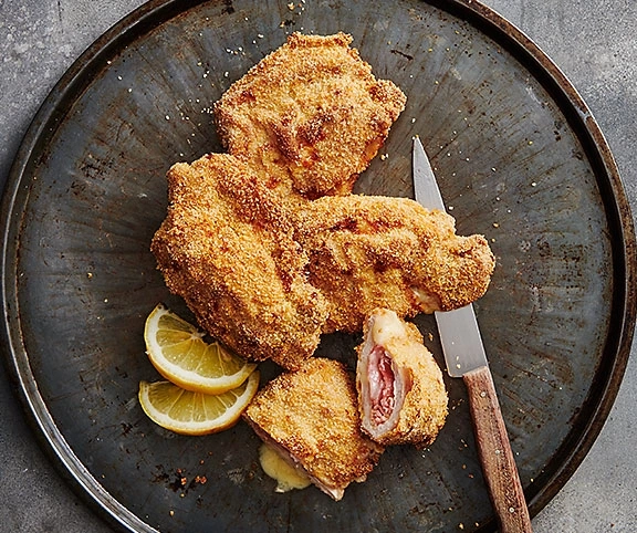 Hähnchen-Cordon-Bleu auf einem Teller mit Zitrone und Messer