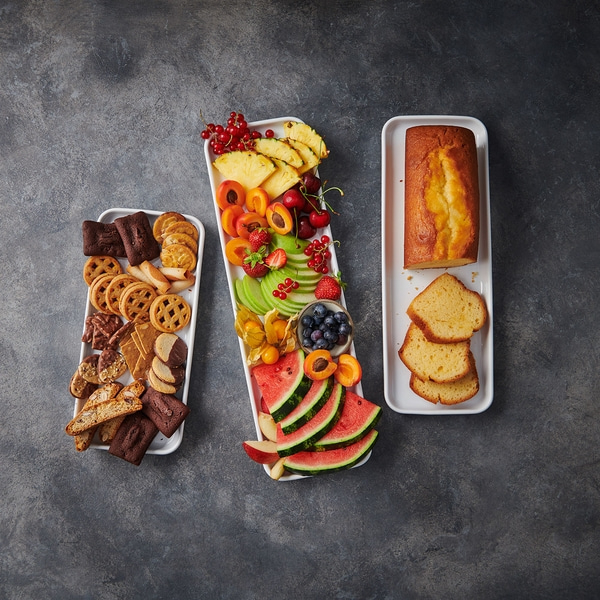 Plateaux de fruits et gâteaux sur fond gris, présentation culinaire.