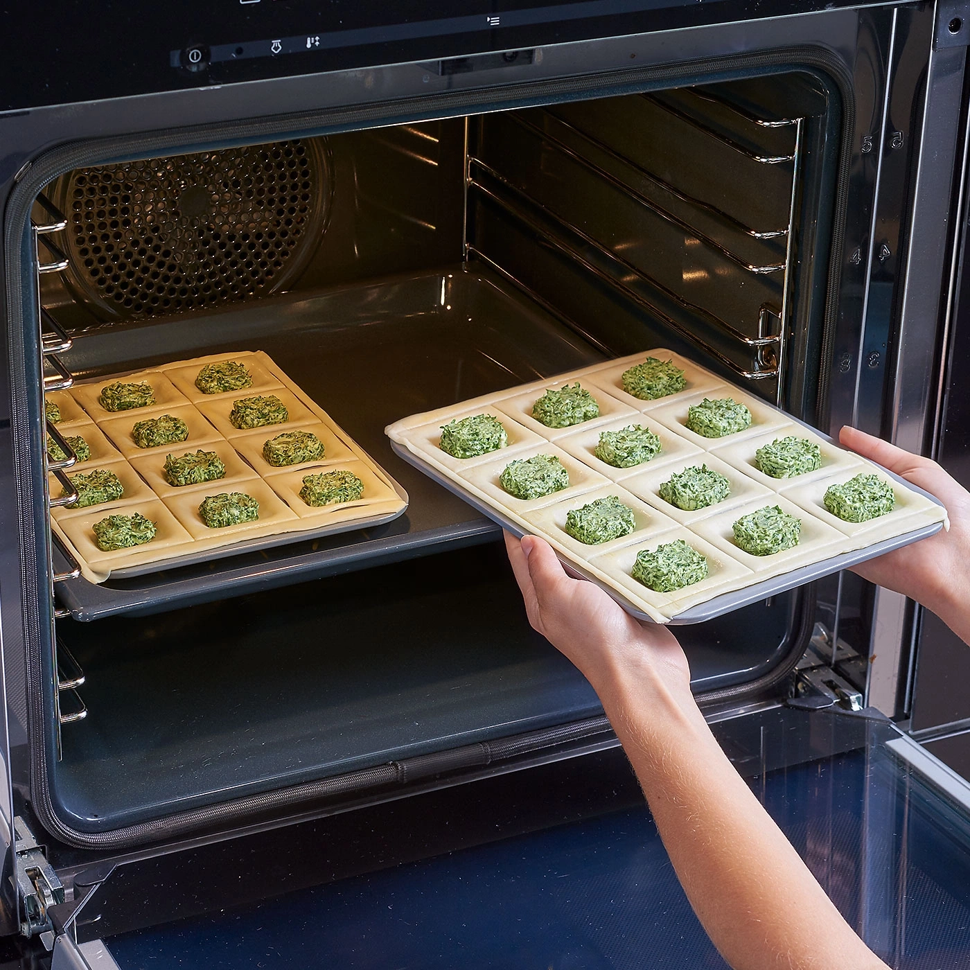 Backofen mit Ravioli auf Backblechen, bereit zum Backen. Kochen in der Küche.