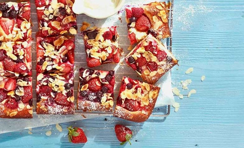 Kuchen mit Beeren und Mandeln auf blauem Tisch, lecker und süß