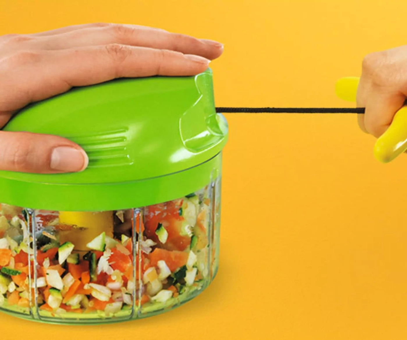 Une main tire un hachoir avec des légumes.