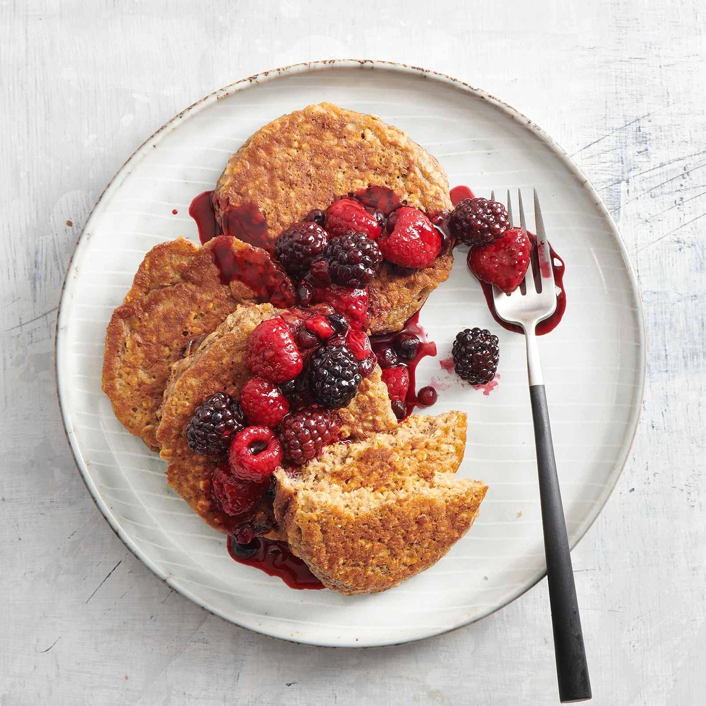 Pfannkuchen mit Beeren und Soße auf einem Teller mit Gabel