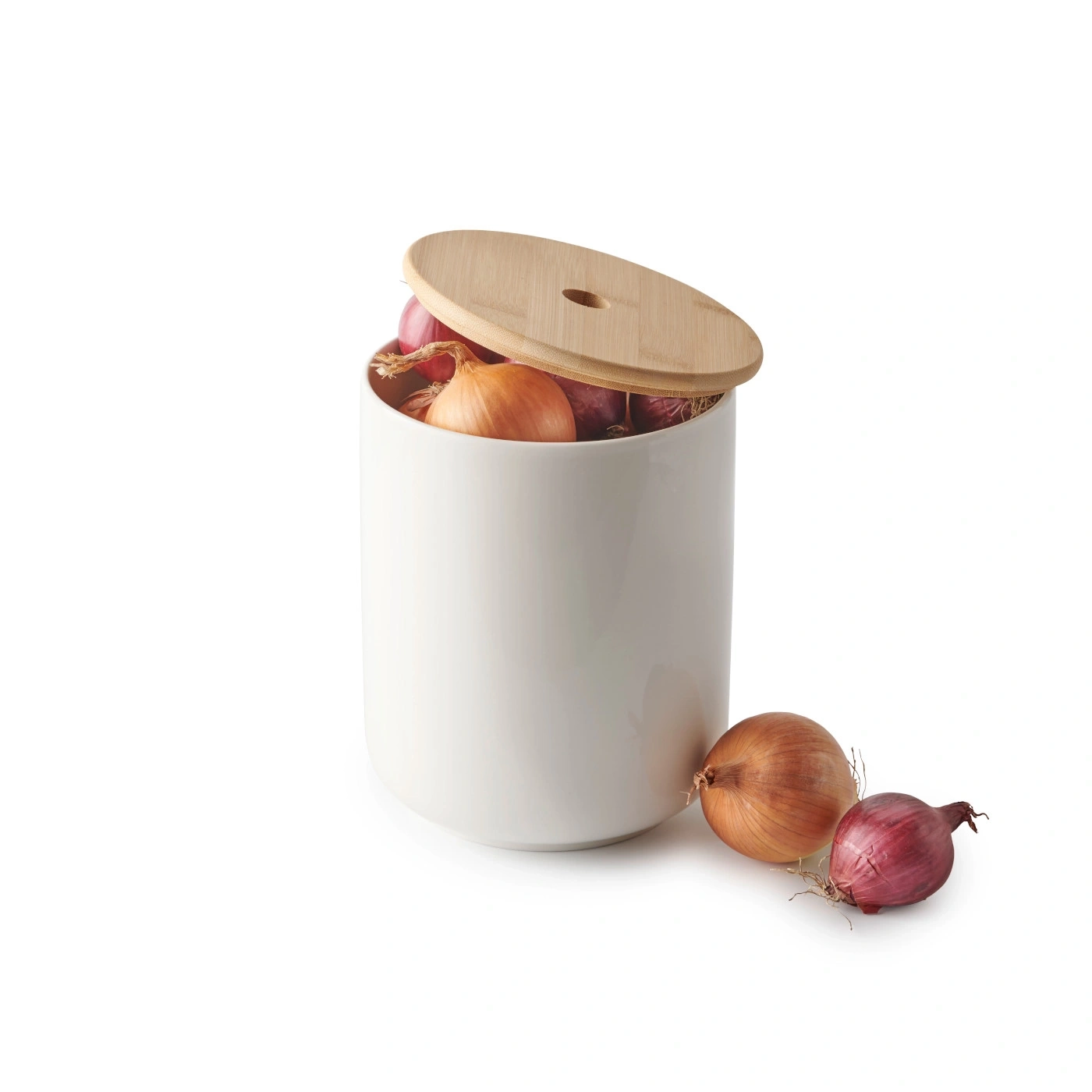 Récipient blanc avec couvercle, rempli d'oignons, avec deux oignons à côté.