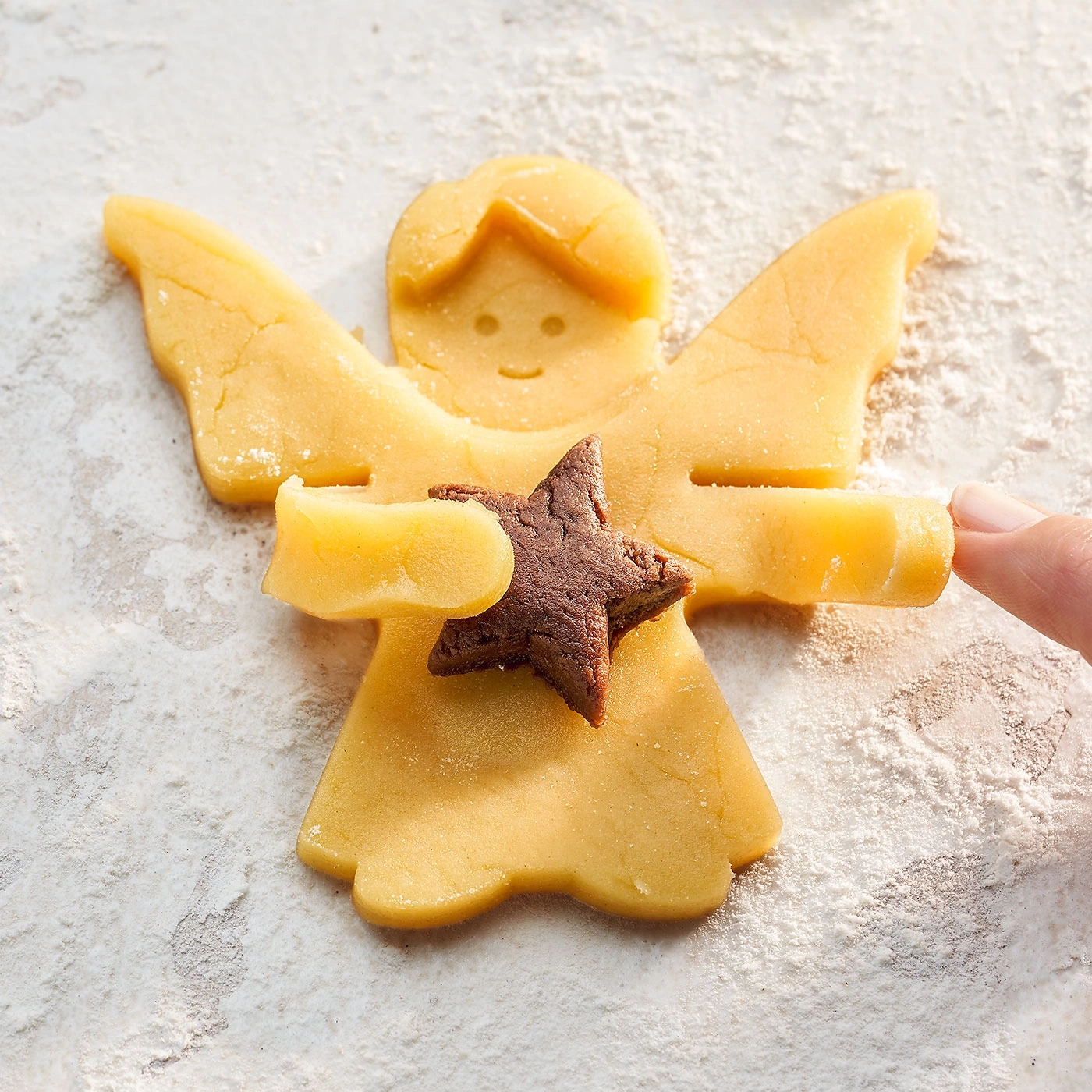 Biscuit ange avec étoile, sur une surface saupoudrée de farine, gros plan.