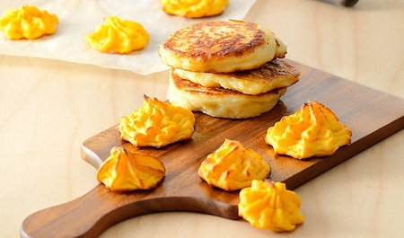 Ein Holzbrett mit Kartoffelpuffern und Pfannkuchen, Nahaufnahme.