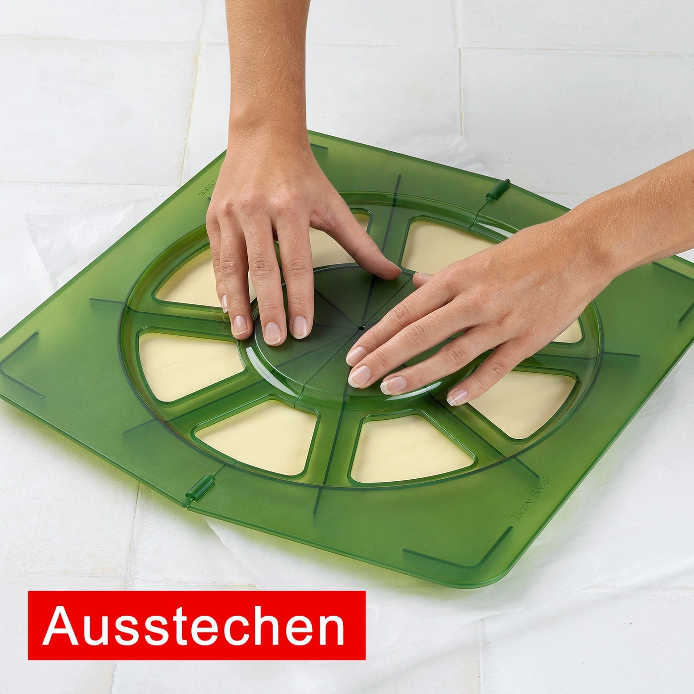 Hände benutzen grünes Werkzeug zum Ausstechen von Teig. Backen, Küche, Kochen.