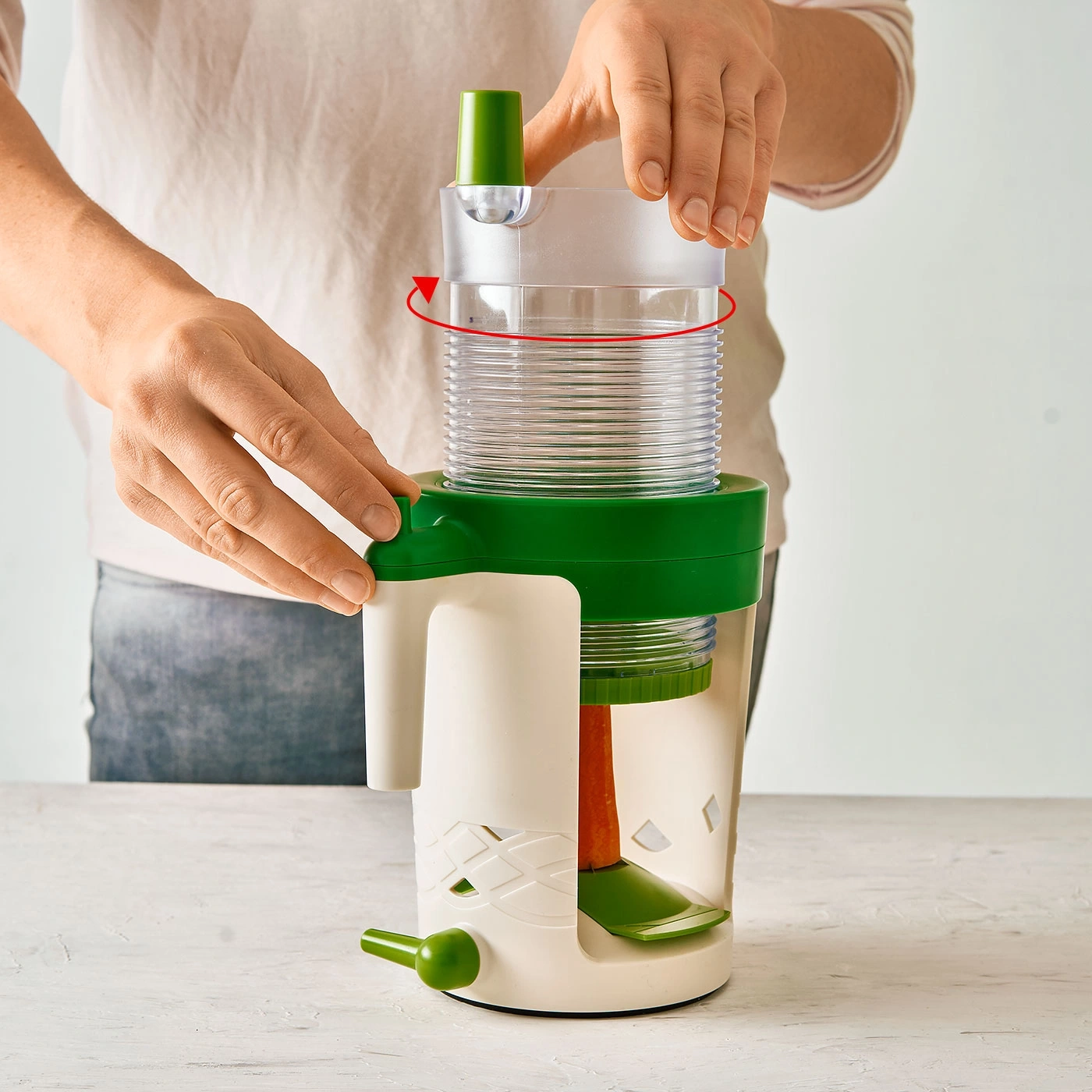 Une personne tourne un coupe-légumes vert et blanc pour l'utiliser.