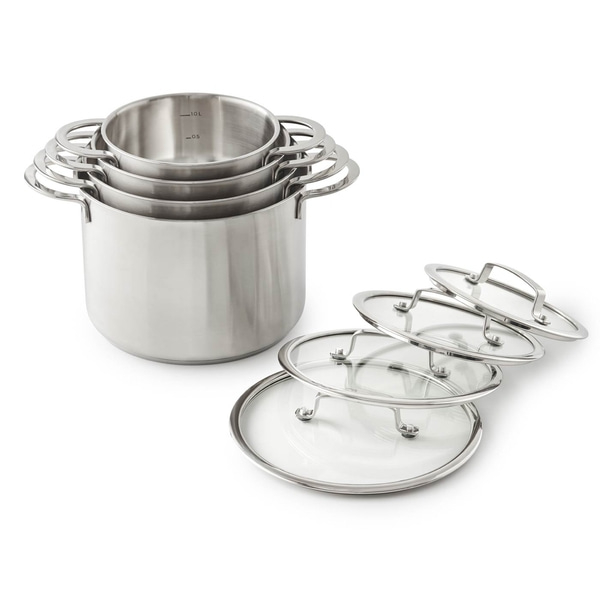 Ensemble de casseroles en acier inoxydable avec couvercles en verre, empilées et isolées sur fond blanc