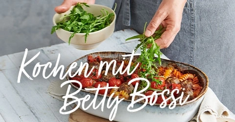 Person fügt Rucola zu einem Gericht mit Betty Bossi hinzu.