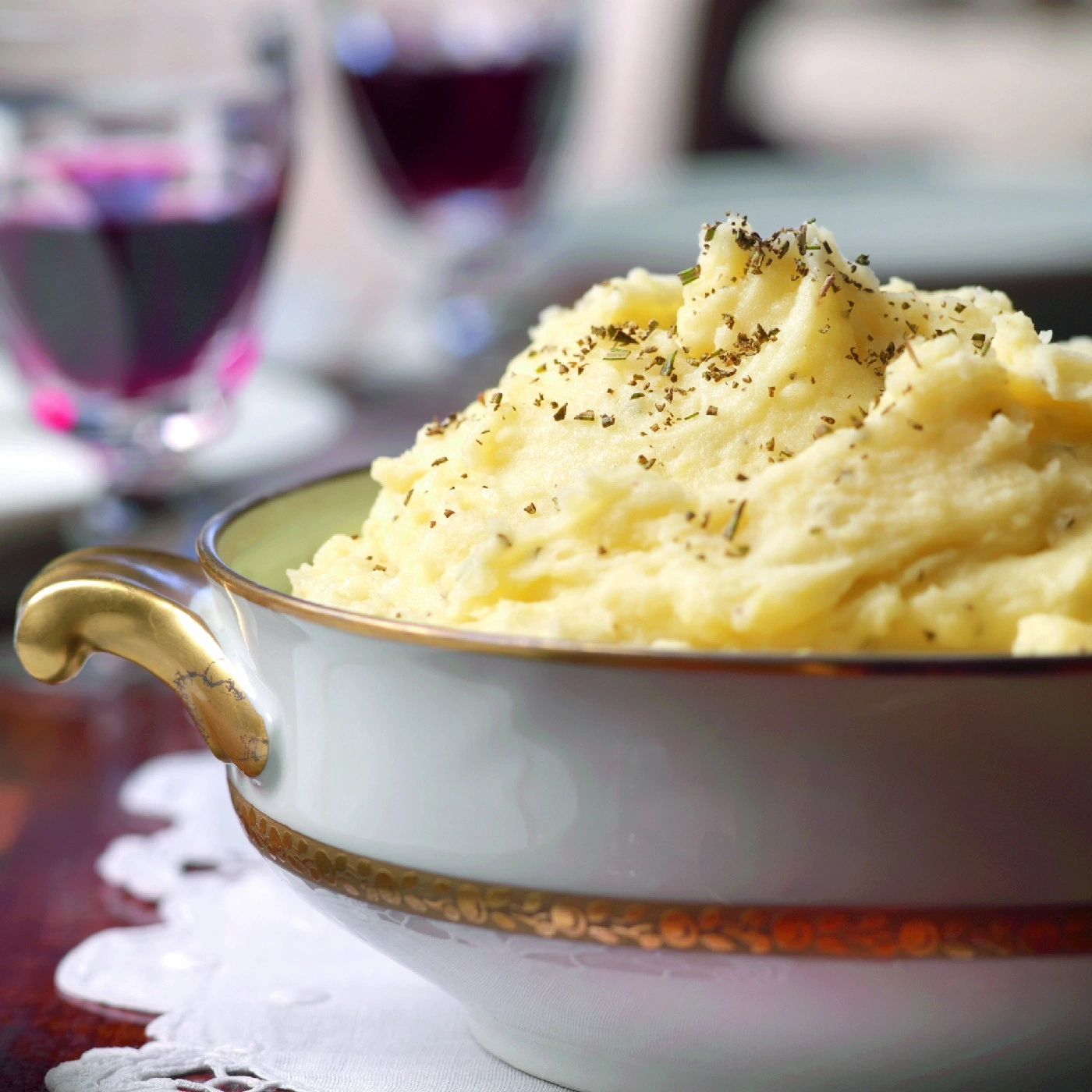 Nahaufnahme von Kartoffelpüree in einer Schüssel mit Wein im Hintergrund.