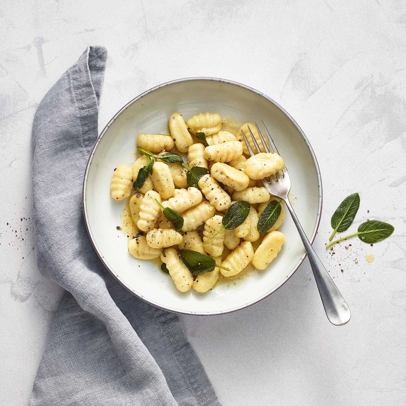 Gnocchi mit Salbei und Pfeffer auf einem Teller mit Gabel und Servietten