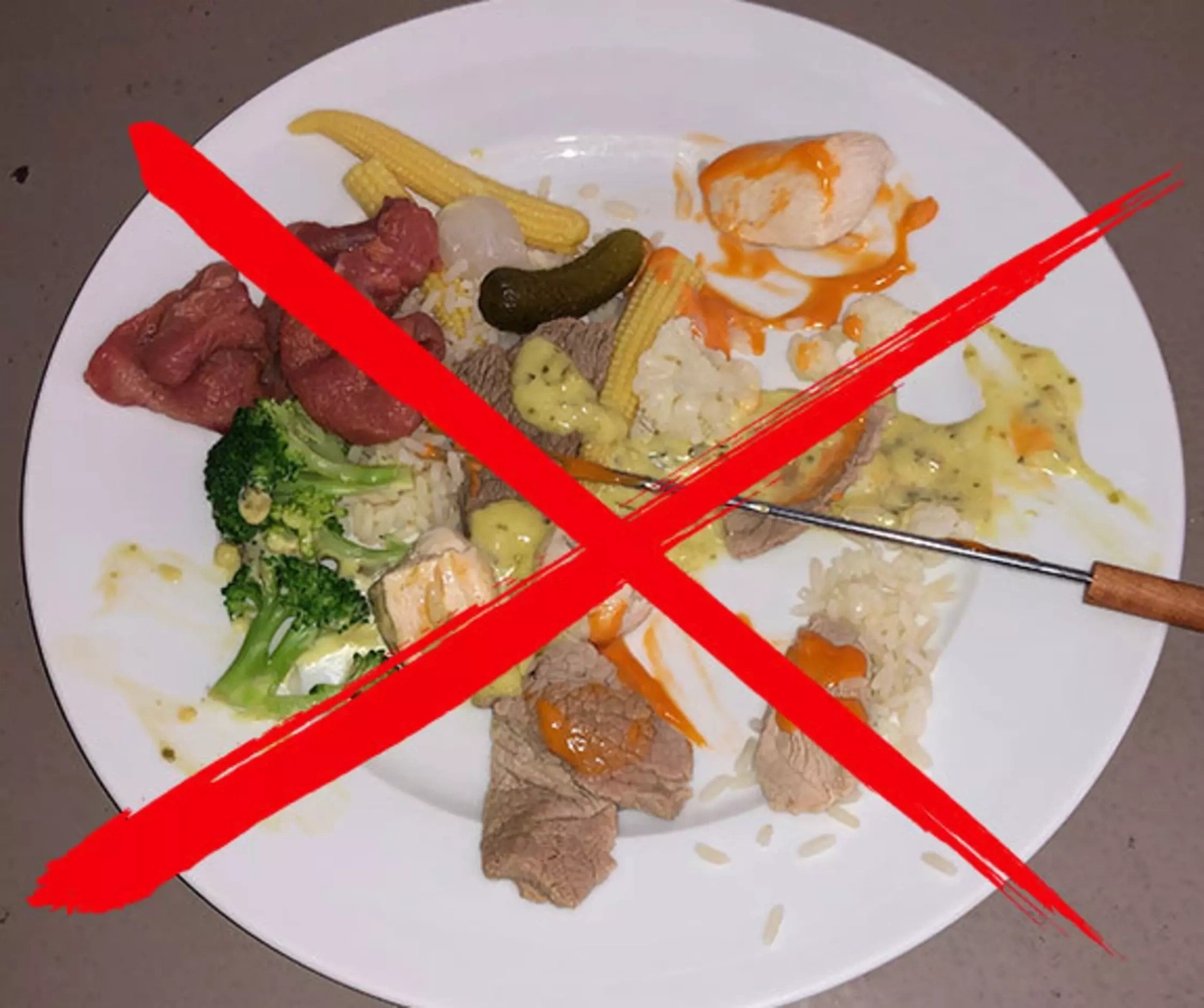 Assiette de viande, riz, légumes et sauce, barrée.