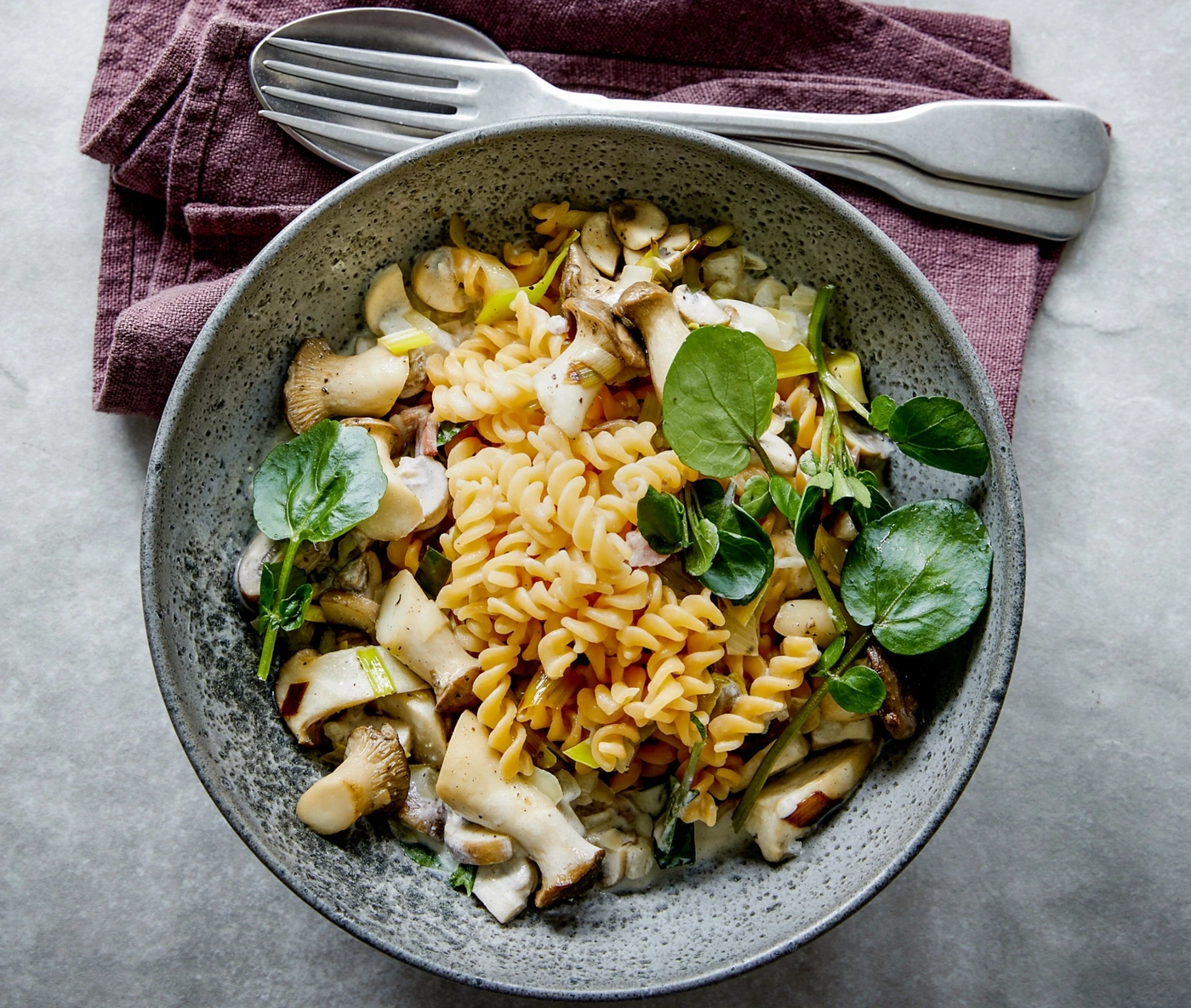 Pasta mit Pilzen und Kräutern in einer Schüssel mit Besteck und Serviette
