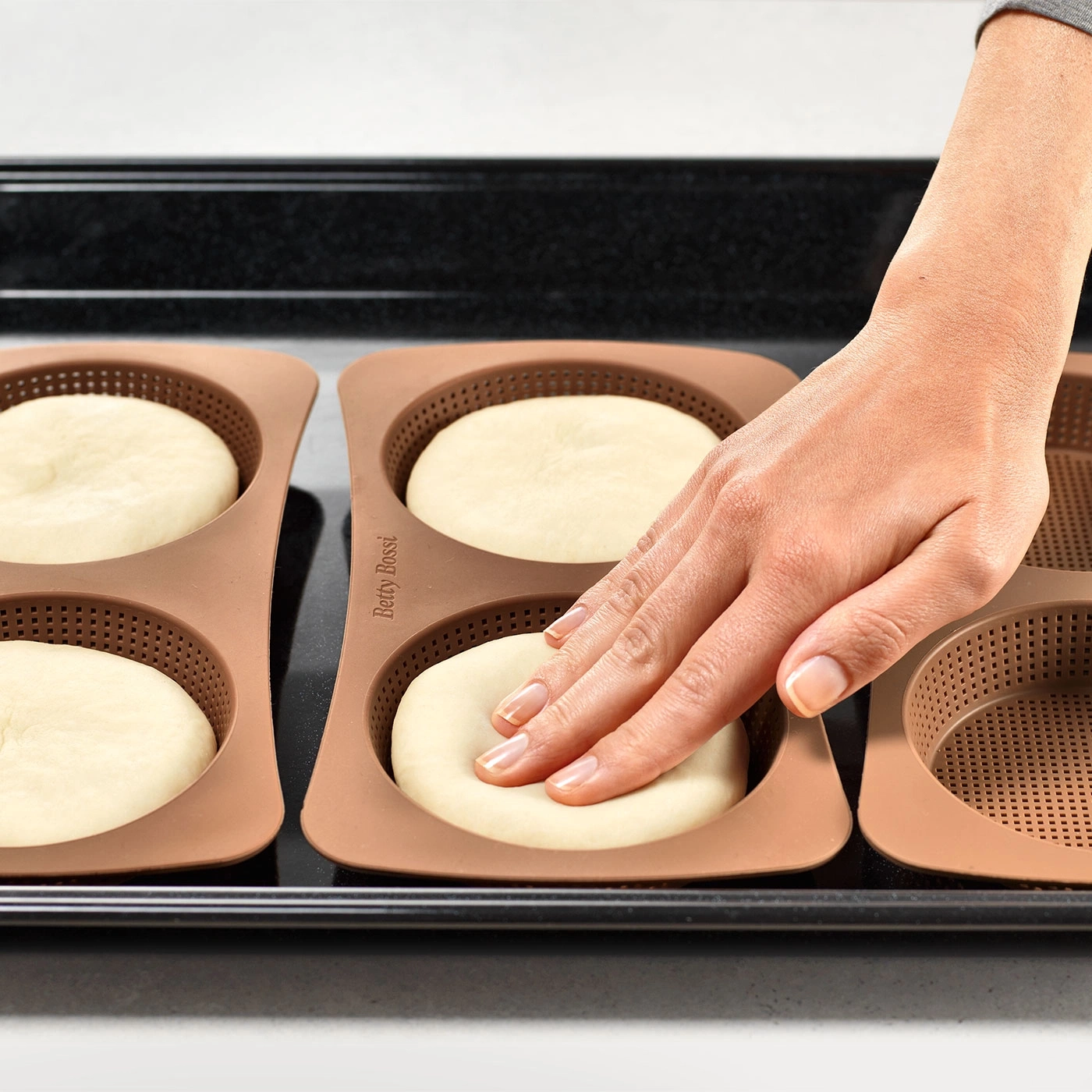 Hand berührt Teig in Backform auf Backblech. Backen, Küche, Essen, Brot.