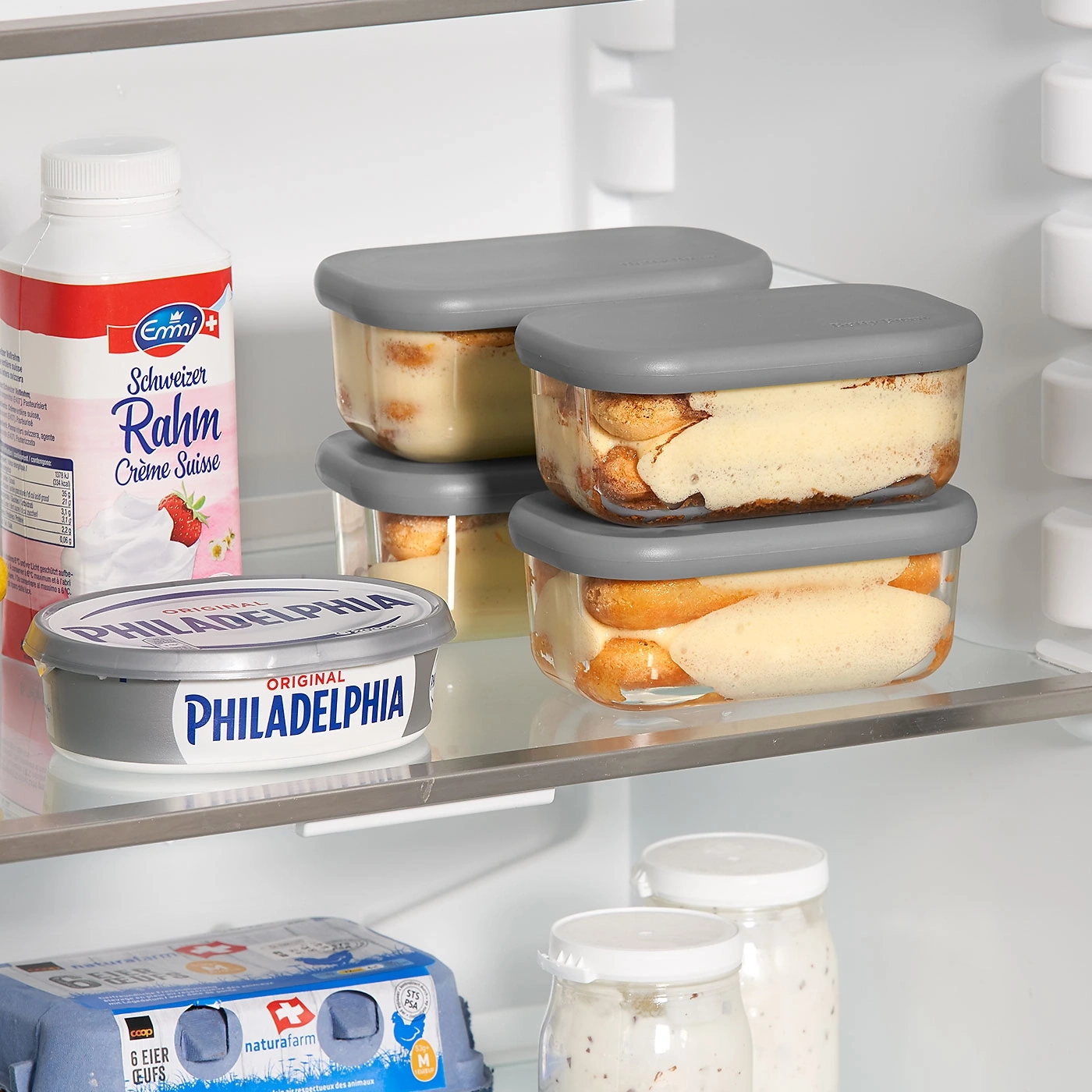 Réfrigérateur avec tiramisu, crème, Philadelphia, œufs et bocaux.