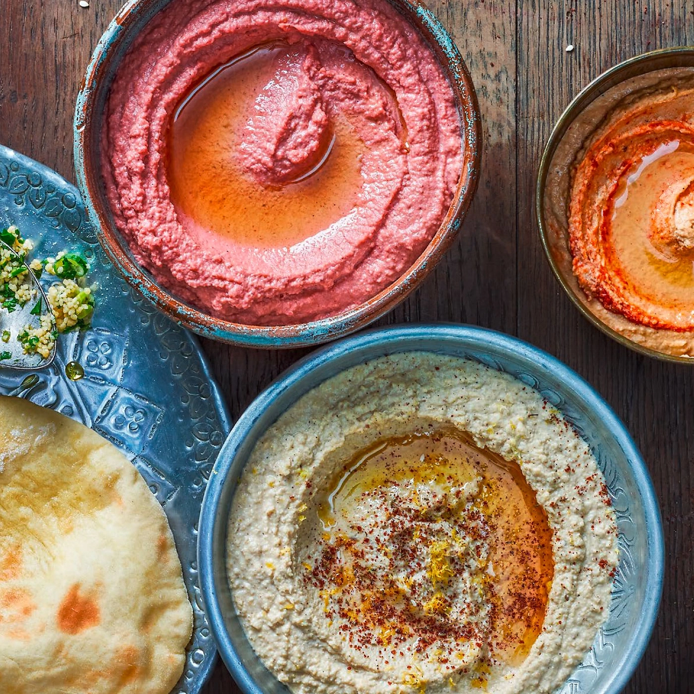 Plats de houmous avec pain et accompagnements sur une table en bois