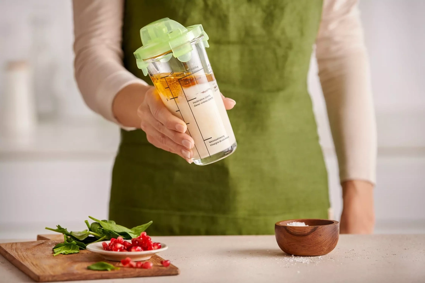 Une personne tient une bouteille de vinaigrette et des ingrédients de cuisine.