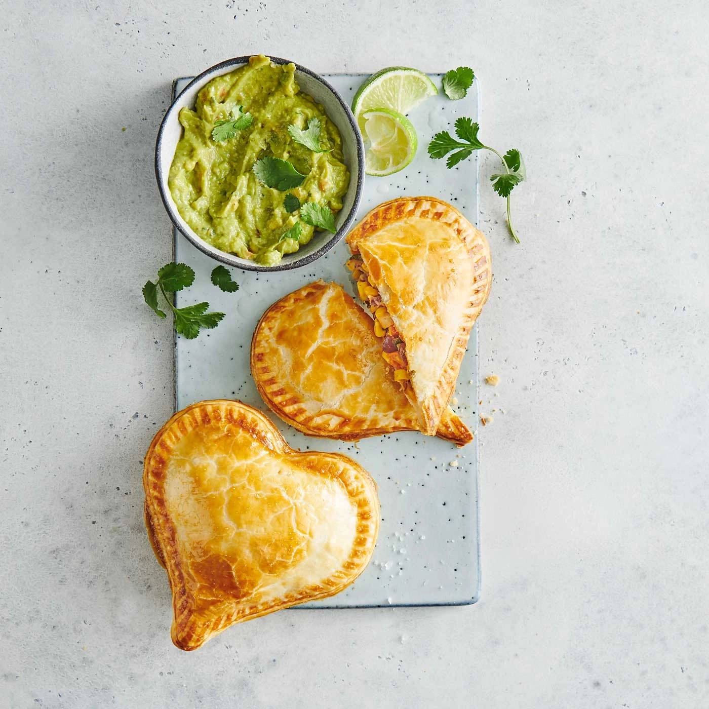 Des pâtés en forme de cœur avec du guacamole et de la lime sur un plateau
