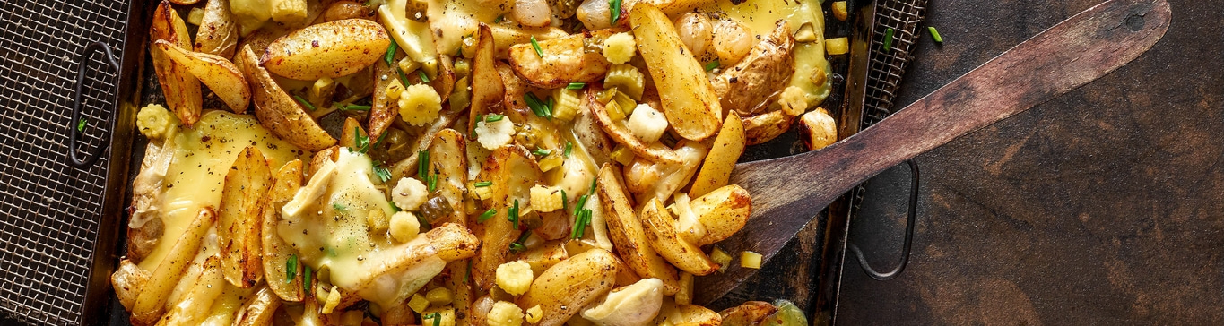 Gebratene Kartoffeln mit Käse und Gemüse, serviert auf einem Tablett.