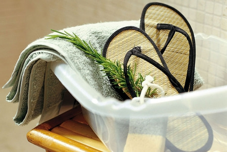 Entspannungs-Set mit Handtuch, Flip-Flops und Kräutern in einer Wanne