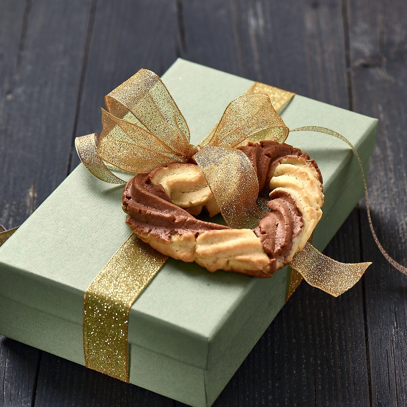 Geschenkbox mit Schleife und Keksen, auf dunklem Holz