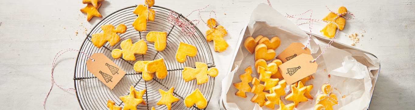 Weihnachtsplätzchen in verschiedenen Formen auf einem Rost und in einer Schachtel.