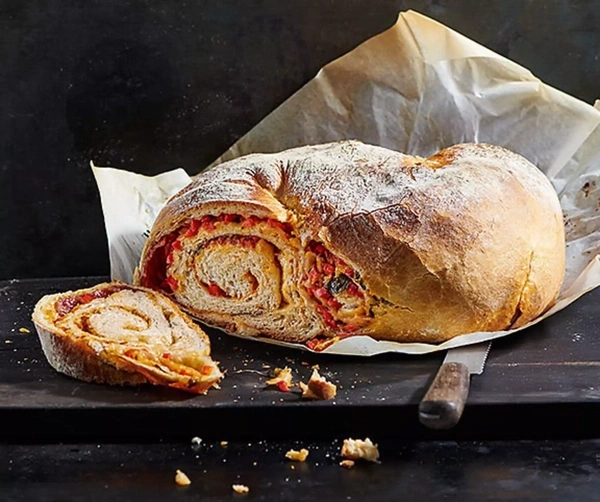 Brot mit roten und gelben Füllungen, auf Backpapier, daneben ein Messer.