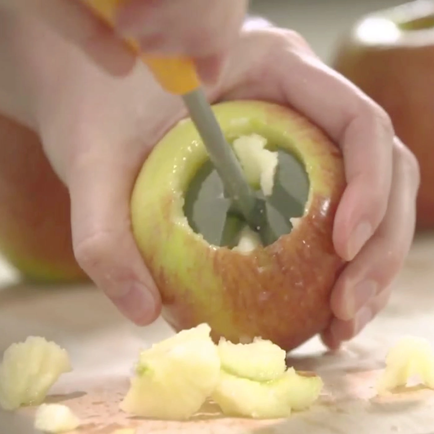 Apfel wird mit einem Werkzeug ausgehöhlt, um das Kerngehäuse zu entfernen.